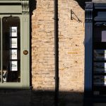 Sunlit display windows of an estate agency in Malmesbury, England.